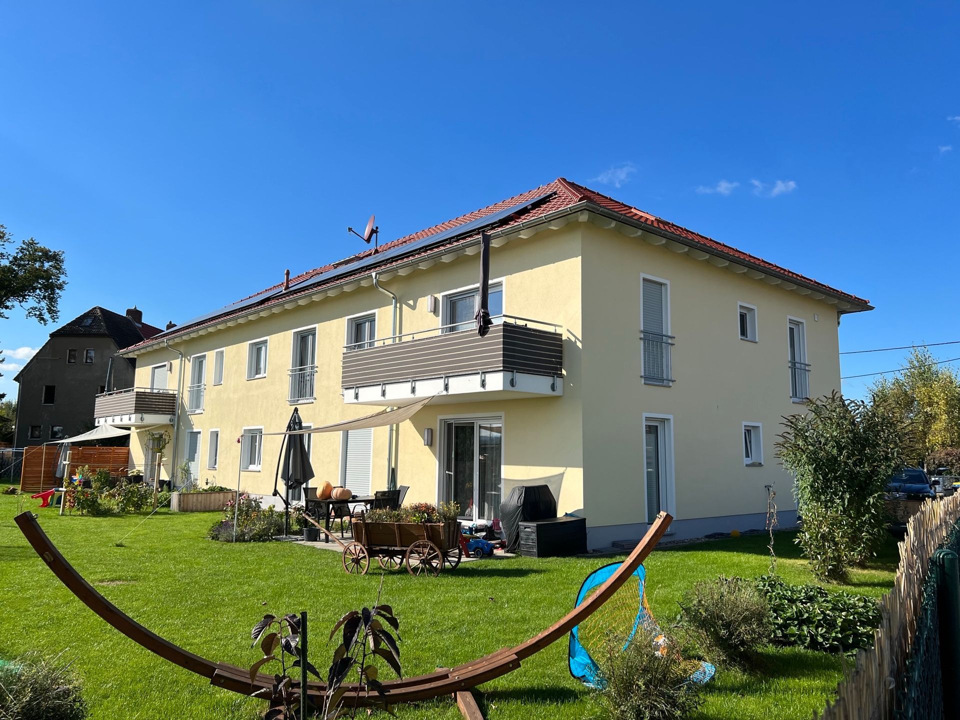 Gelbes Mehrfamilienhaus mit Garten und Terrassennutzung