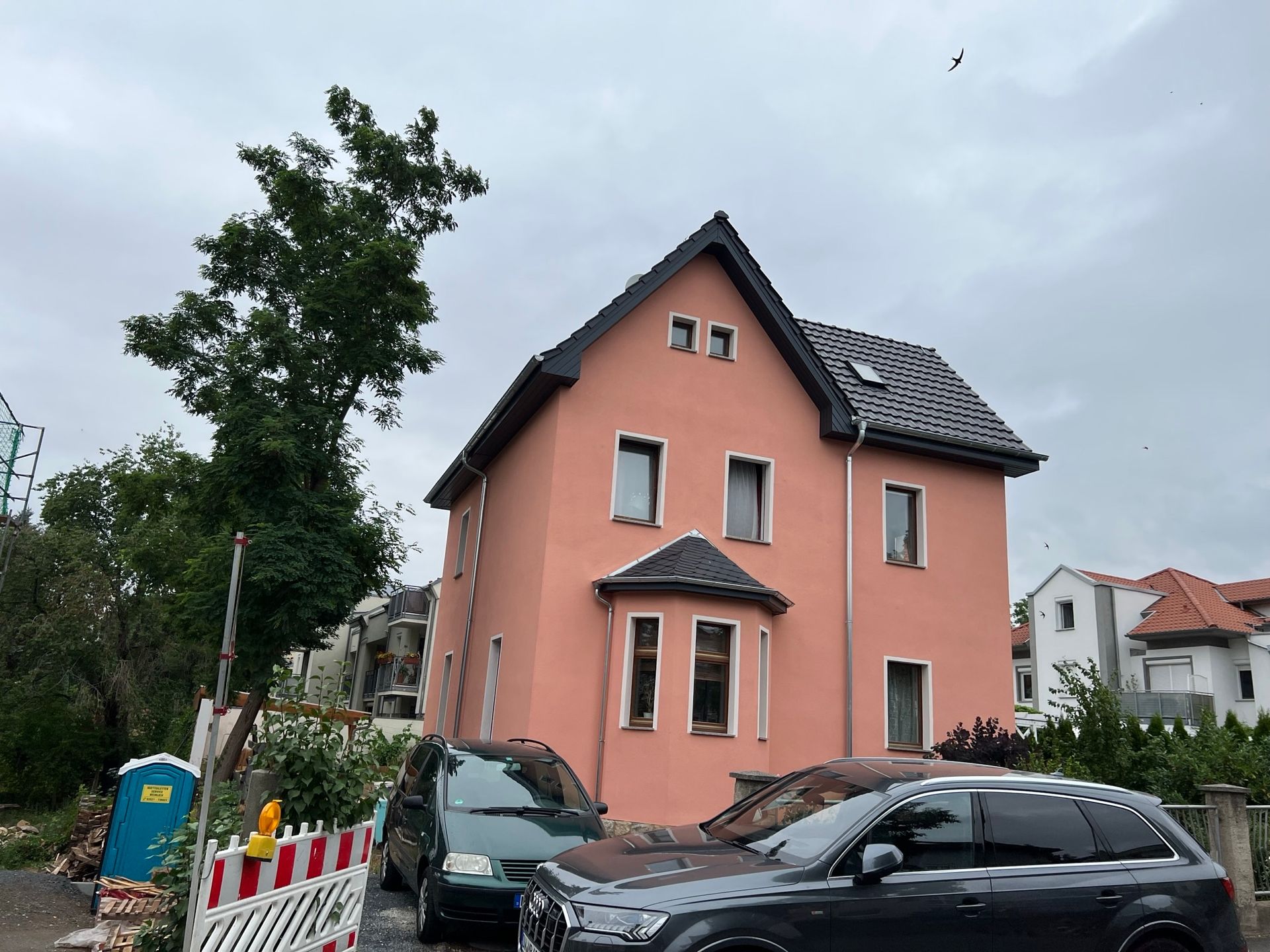 Rosa Wohnhaus mit Baum und Baufeld